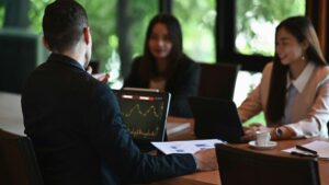 Three business people sit around a table during a meeting, for “How Dentists Can Make Their Money Work Harder with the Note E”