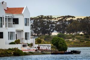 Exterior, a lake house with tall trees in the background, for “How Empty Nesters Can Build Wealth with the Note E”