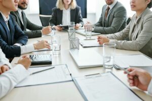 Interior, several suited professionals sit around a round table during a meeting, for “Recently Inherited Money? Here’s How the Note I Can Help It Flourish”